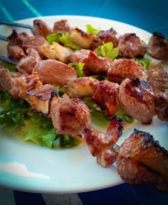 Delicious grilled meat skewers on a bed of fresh greens, perfect for a barbecue meal.