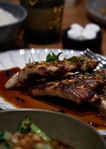Delicious grilled pork ribs with herbs and sauce on a plate, perfect for a gourmet meal.